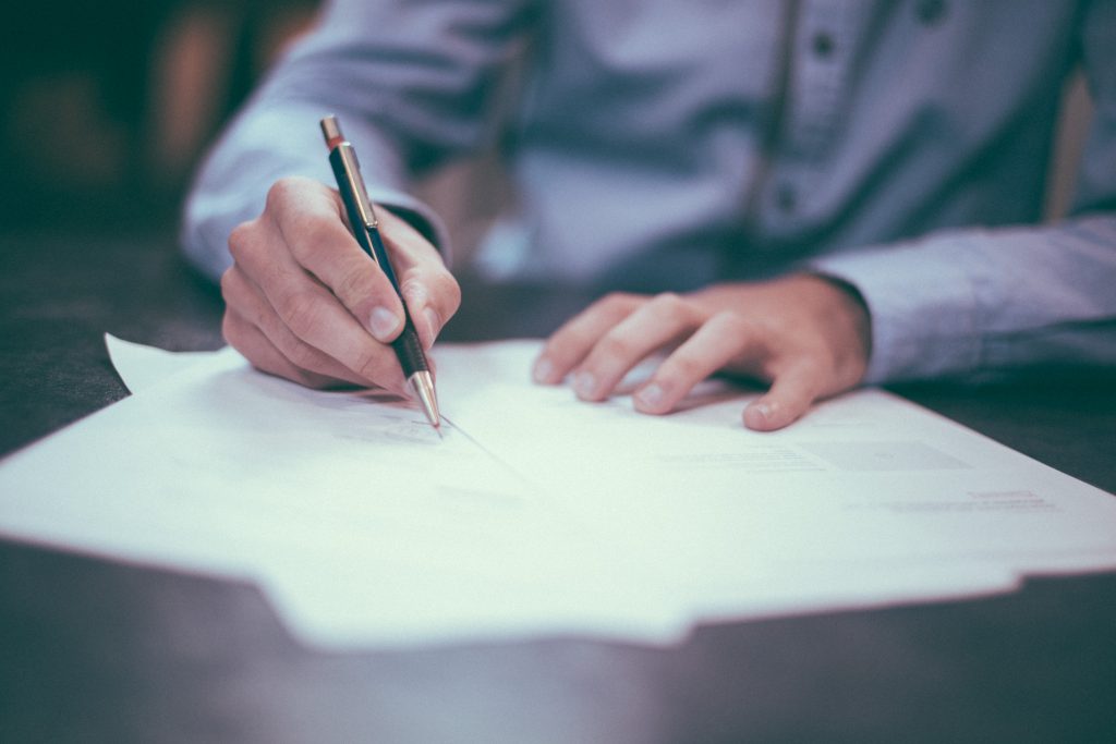 person sitting and writing on piece of paper