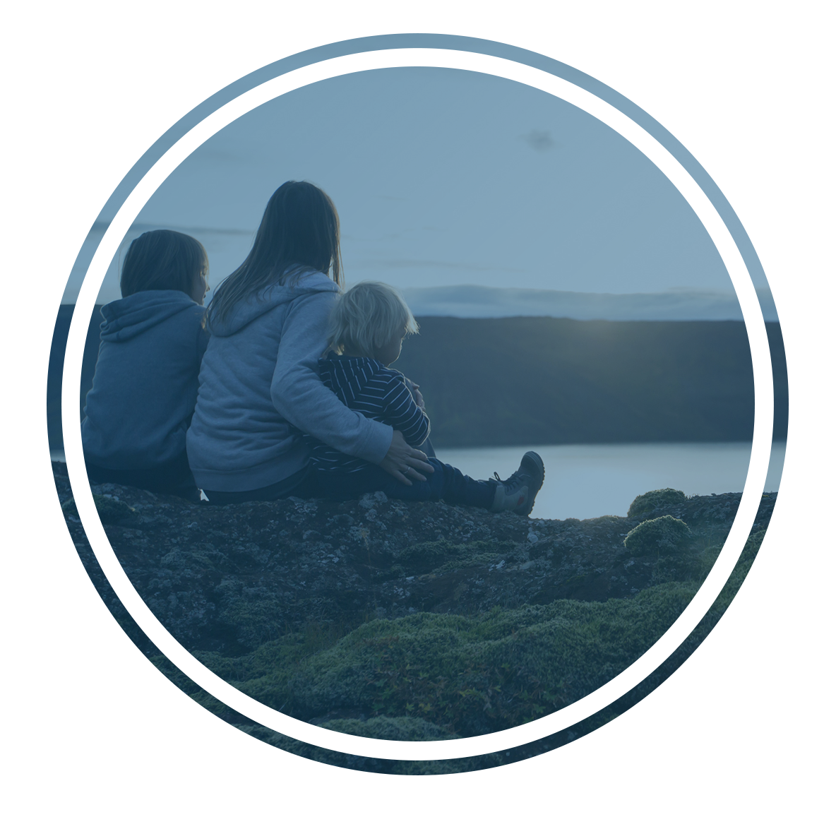 mother sitting with two kids overlooking water